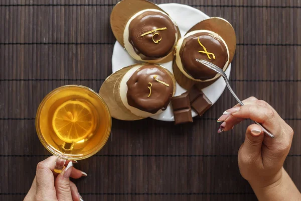 Koyu ahşap arka plan üzerinde çay pasta. Erkek bir arka plan kek ve bir bardak çay üzerinde eller.