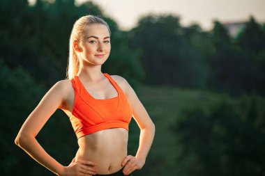 Doğa spor egzersizleri yapıyor kırmızı bir üst ve siyah pantolon içinde genç bir sarışın.