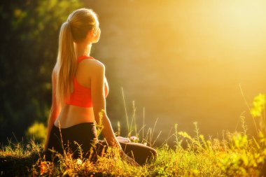 Kırmızı Top bir genç bir sarışın Fitness doğada çimlerin üzerine oturur. Bir sporcumuz jimnastik için hazırlar.