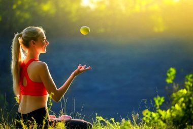 Kırmızı Top bir genç bir sarışın doğada çimlerin üzerine oturur. Sportif bir kadın tutar atar onu elinde bir yeşil elma