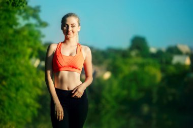 Genç sarışın kadın doğada yapıyor. Kırmızı yelek bir spor kız Nehri yakınında bir parkta duruyor