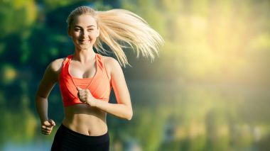 doğa üzerinde çalışan genç sarışın bir kadın. Bir kırmızı bir spor kız T-shirt Nehri yakınında park boyunca çalışır.