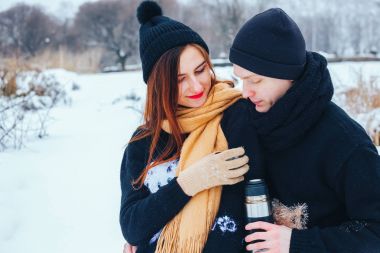 Genç çift termos içinde kış orman sıcak çay dökülen