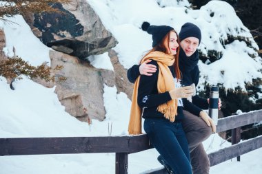 Genç çift termos içinde kış orman sıcak çay dökülen