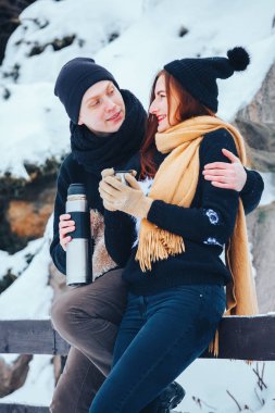 Genç çift termos içinde kış orman sıcak çay dökülen