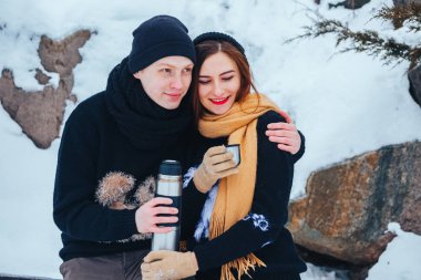 Genç çift termos içinde kış orman sıcak çay dökülen