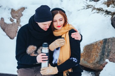 Genç çift termos içinde kış orman sıcak çay dökülen