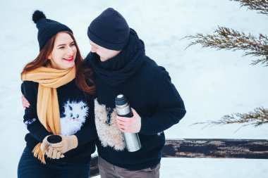 Genç çift termos içinde kış orman sıcak çay dökülen