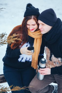 Genç çift termos içinde kış orman sıcak çay dökülen