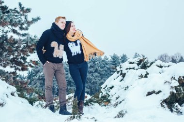 Adam ve kız kış ormanlarında dinleniyorlar. Karda karı-koca. Genç bir çift kış parkında yürüyor..