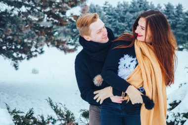 Adam ve kız kış ormanlarında dinleniyorlar. Karda karı-koca. Genç bir çift kış parkında yürüyor..