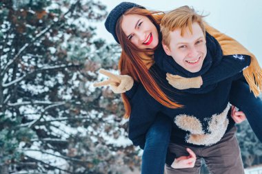 Adam ve kız kış ormanlarında dinleniyorlar. Karda karı-koca. Genç bir çift kış parkında yürüyor..