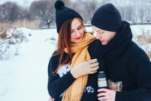 Genç çift termos içinde kış orman sıcak çay dökülen