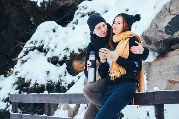 Genç çift termos içinde kış orman sıcak çay dökülen