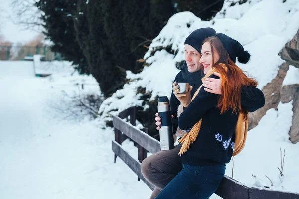 Genç çift termos içinde kış orman sıcak çay dökülen