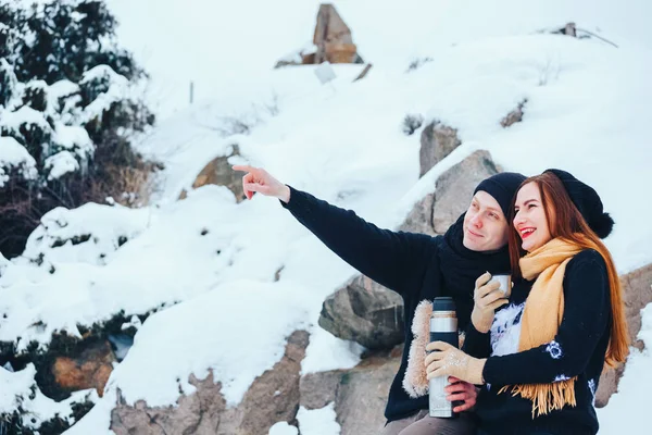 Genç çift termos içinde kış orman sıcak çay dökülen