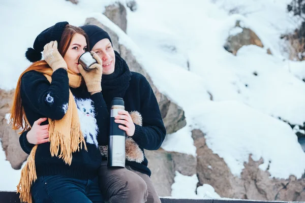 Genç çift termos içinde kış orman sıcak çay dökülen