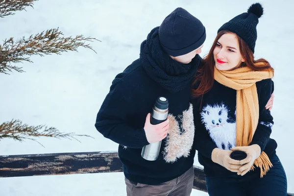 Genç çift termos içinde kış orman sıcak çay dökülen