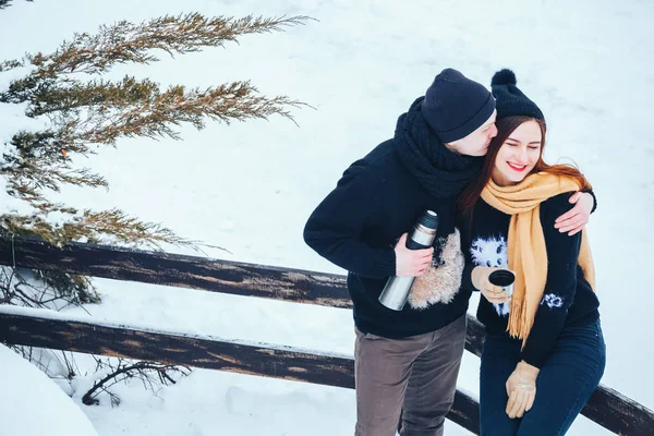 Genç çift termos içinde kış orman sıcak çay dökülen