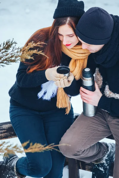 Genç çift termos içinde kış orman sıcak çay dökülen