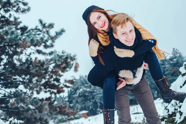 O tipo e a rapariga descansam no bosque de Inverno. Marido e mulher na neve. Jovem casal caminhando no parque de inverno. — Fotografia de Stock