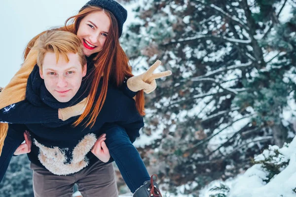 Парень и девушка отдыхают в зимнем лесу. Муж и жена в снегу. Молодая пара, гуляющая в зимнем парке. — стоковое фото