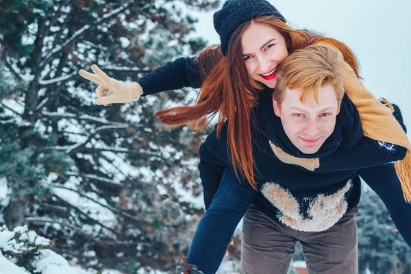 Adam ve kız kış ormanlarında dinleniyorlar. Karda karı-koca. Genç bir çift kış parkında yürüyor..