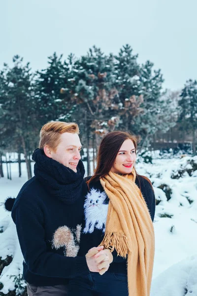 Парень и девушка отдыхают в зимнем лесу. Муж и жена в снегу. Молодая пара, гуляющая в зимнем парке. — стоковое фото