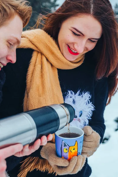 Genç çift ahşap aşık. Adam bir termos çay dökülen. Yakın çekim