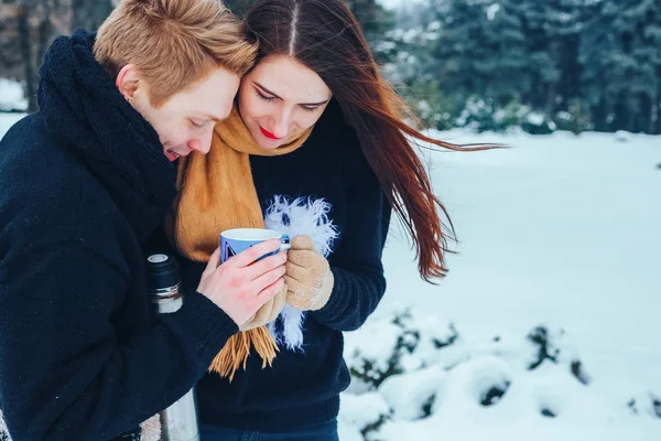 Pareja joven enamorada en madera. El hombre vierte té de un termo. Primer plano — Foto de Stock