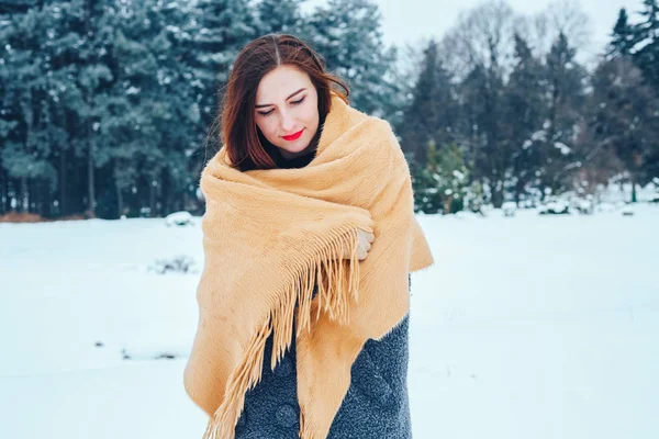 Mujer joven pelirroja con una bufanda roja en un bosque de invierno — Foto de Stock