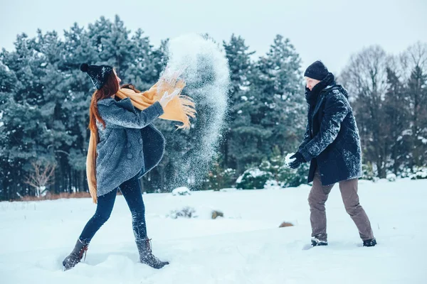 Adam ve kız kış ormanlarında dinleniyorlar. Karda karı-koca. Genç bir çift kış parkında yürüyor..