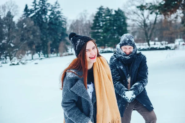 Killen och flickan vilar i vinterskogen. Make och hustru i snön. Unga par promenader i vinter park. — Stockfoto