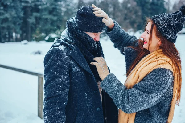 O tipo e a rapariga descansam no bosque de Inverno. Marido e mulher na neve. Jovem casal caminhando no parque de inverno. — Fotografia de Stock