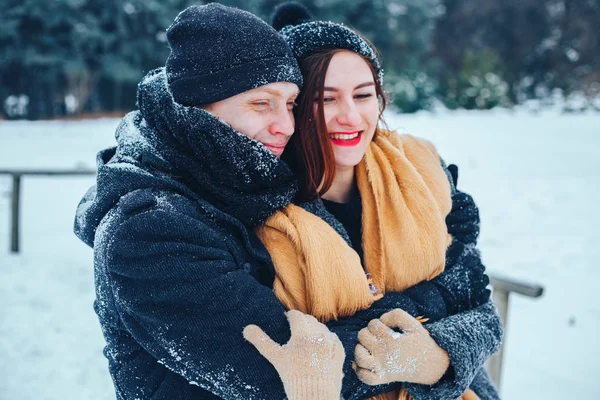 O tipo e a rapariga descansam no bosque de Inverno. Marido e mulher na neve. Jovem casal caminhando no parque de inverno. — Fotografia de Stock