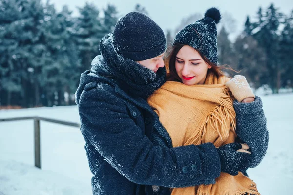 Der Kerl und das Mädchen ruhen sich im Winterwald aus. Mann und Frau im Schnee. Junges Paar spaziert im Winterpark. — Stockfoto