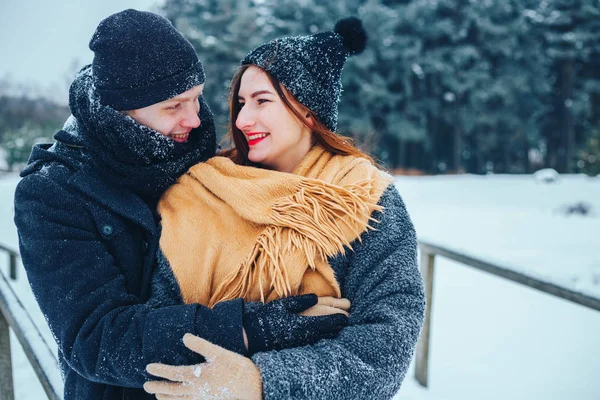 O tipo e a rapariga descansam no bosque de Inverno. Marido e mulher na neve. Jovem casal caminhando no parque de inverno. — Fotografia de Stock