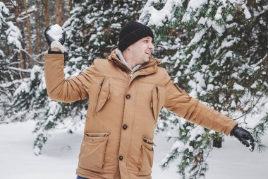 Kırmızı ceketli adamı kış ormanda bir kartopu atar. oynak
