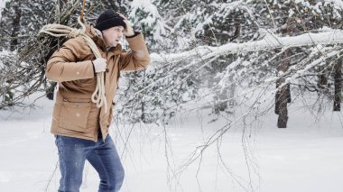 çırpı ve kış ormanın içinde bir ip ile kırmızı bir ceket bir adam. Yakacak odun adam toplar