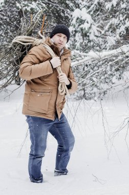 çırpı ve kış ormanın içinde bir ip ile kırmızı bir ceket bir adam. Yakacak odun adam toplar