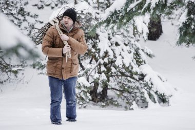 çırpı ve kış ormanın içinde bir ip ile kırmızı bir ceket bir adam. Yakacak odun adam toplar