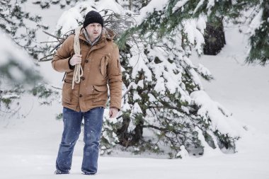 çırpı ve kış ormanın içinde bir ip ile kırmızı bir ceket bir adam. Yakacak odun adam toplar