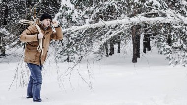 çırpı ve kış ormanın içinde bir ip ile kırmızı bir ceket bir adam. Yakacak odun adam toplar