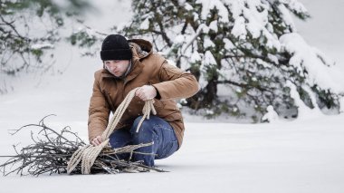 çırpı ve kış ormanın içinde bir ip ile kırmızı bir ceket bir adam. Yakacak odun adam toplar