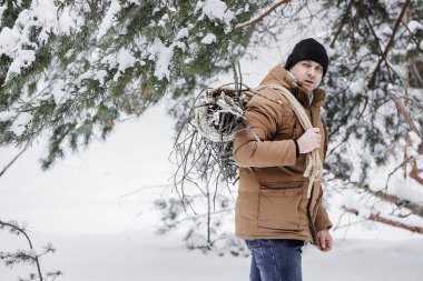 çırpı ve kış ormanın içinde bir ip ile kırmızı bir ceket bir adam. Yakacak odun adam toplar