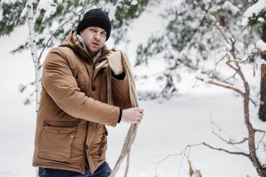 çırpı ve kış ormanın içinde bir ip ile kırmızı bir ceket bir adam. Yakacak odun adam toplar