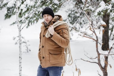 çırpı ve kış ormanın içinde bir ip ile kırmızı bir ceket bir adam. Yakacak odun adam toplar