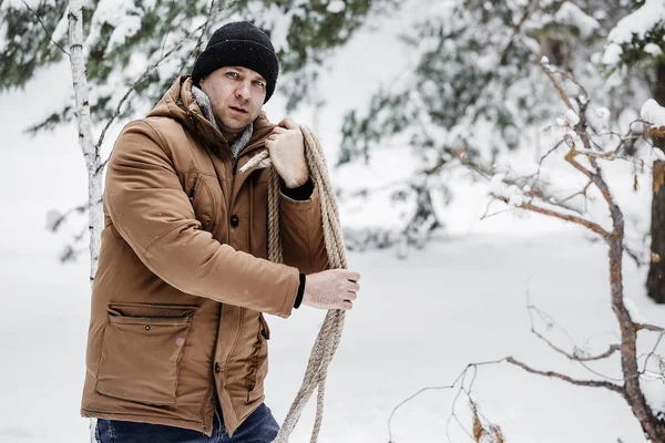 çırpı ve kış ormanın içinde bir ip ile kırmızı bir ceket bir adam. Yakacak odun adam toplar