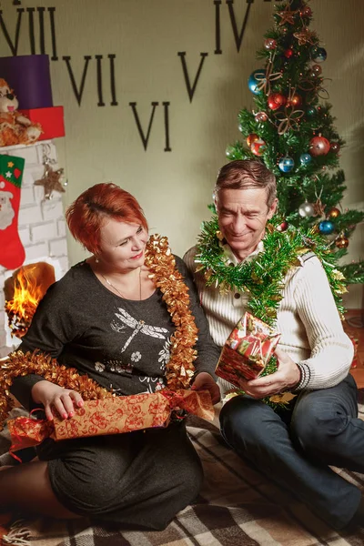 Fröhliche Frau und Mann sitzen am Weihnachtsbaum — Stockfoto