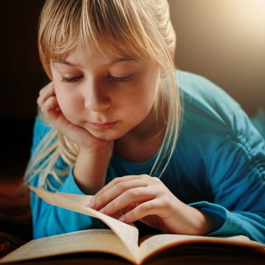 küçük sarışın kız mavi bluz içinde karanlık bir odada yatıyor ve bir yeşil kitap okur